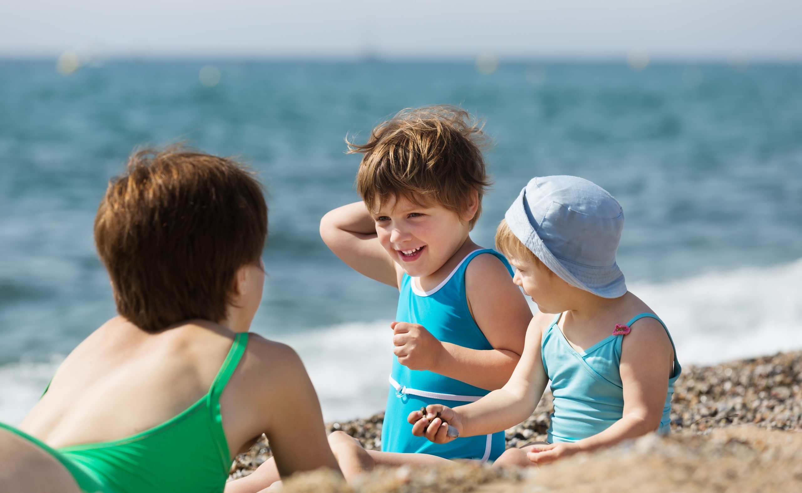 Niños pequeños jugando en la playa durante las vacaciones de verano para ilustrar consejos de salud infantil.